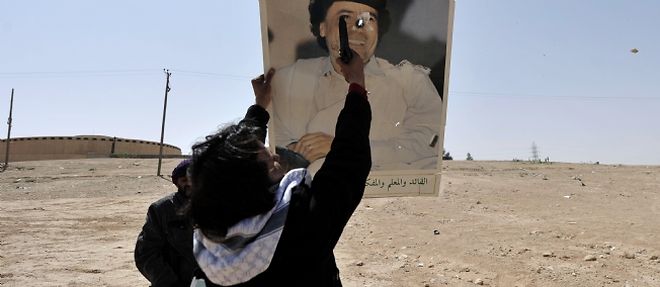 Un rebelle libyen s'entraine a tirer sur le portrait de Kadhafi, le 27 mars