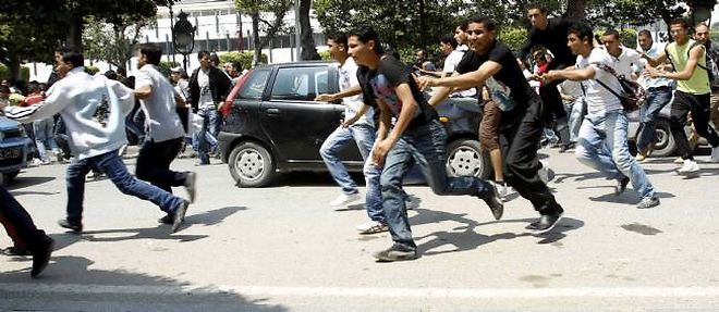 De jeunes protestataires tentent d'echapper aux policiers lors d'une manifestation contre le gouvernement a Tunis, vendredi.