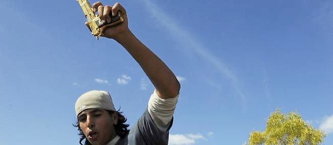 Un jeune combattant du CNT brandit un pistolet plaque or qui serait celui du colonel Kadhafi. 
