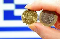 Un drachme et un euro, sur fond de drapeau grec. ©PHILIPPE HUGUEN