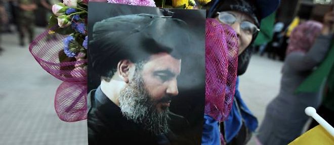 Dans l'attente de la liberation des otages chiites, une femme brandit le portrait du leader du Hezbollah, le 25 mai a l'aeroport de Beyrouth.