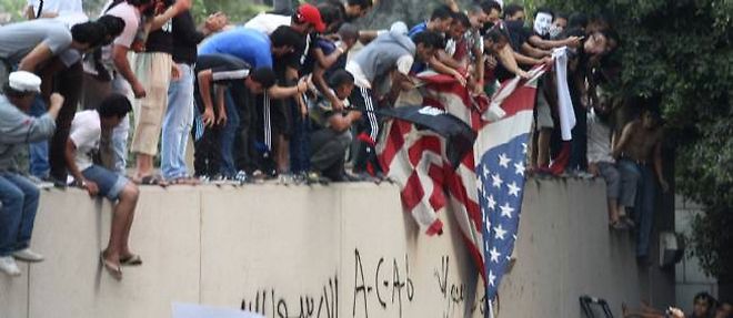 Des manifestants dechirent le drapeau americain.