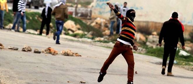 Un etudiant palestinien de l'universite de Birzeit jette une pierre en direction de soldats israeliens, apres une manifestation de soutien a ses compatriotes prisonniers en Israel.