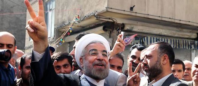 Hassan Rohani, effectuant le "V" de la victoire, a la sortie du bureau de vote ou il vient de deposer son bulletin, vendredi 15 juin 2013.