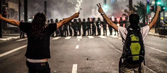 Deux manifestants font face aux forces de l'ordre a Sao Paulo le 12 juin pour protester contre la hausse des prix des transports.