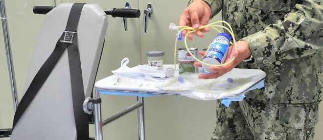 Un membre du personnel medical explique la procedure d'alimentation forcee infligee aux grevistes de la faim a Guantanamo. Aucun journaliste n'a pu y assister "en vrai".