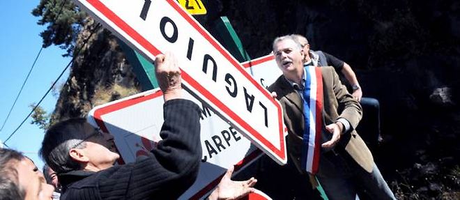 Le chef etoile Michel Bras (a gauche) et le maire Vincent Alazard retirent le panneau signalant l'entree du village, en guise de protestation.