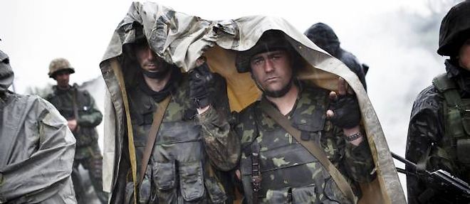 Des soldats ukrainiens se protegeant de la pluie aux abords d'une barricade aux alentours de la ville de Slaviansk, le 2 mai 2014.