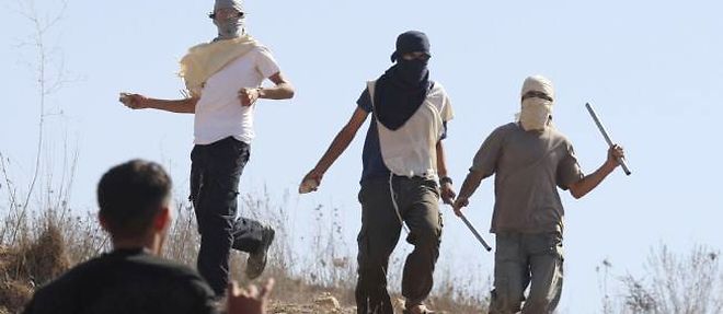 Des colons juifs masques (en haut de la photo) prets a en decoudre avec des habitants du village palestinien d'Assira, en septembre 2011, en Cisjordanie.