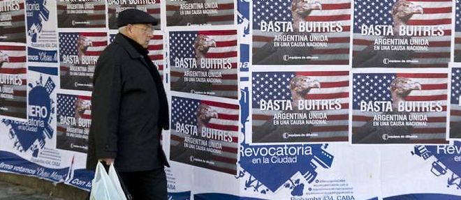 Un homme passe devant des affiches critiquant les fonds vautours, en Argentine.