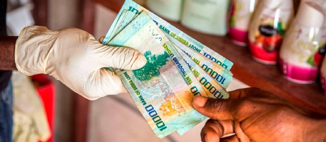 Un signe de l'impact economique d'Ebola en Sierra Leone : ce gant porte par un commercant qui rend la monnaie a un client.