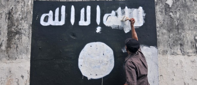 Un employe gouvernemental indonesien efface le drapeau de l'organisation Etat islamique peint sur un mur de la ville de Surakarta City.