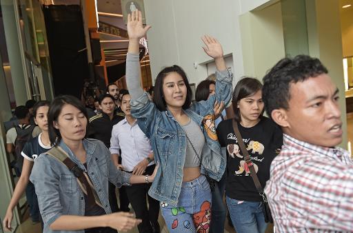 Une étudiante thaïlandaise lève les bras alors qu'elle est escortée par des policiers en civil vers la sortie d'un cinéma, à l'occasion de la sortie du nouvel opus de "Hunger Games", le 20 novembre 2014 à Bangkok © Christophe Archambault AFP
