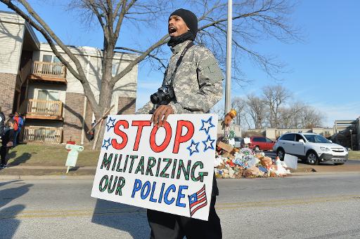 Un homme porte un pancarte demandant l'arrêt de la "militarisation" de la police, lors d'une manifestation à Ferguson (Missouri) le 29 novembre 2014, en mémoire au jeune Noir tué par un policier en août © Michael B. Thomas AFP