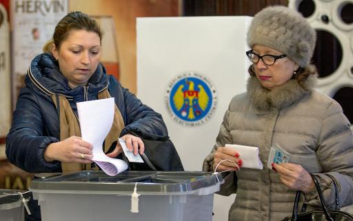Des femmes glissent leur bulletin dans l'urne dans un bureau de vote de Chisinau le 30 novembre 2014