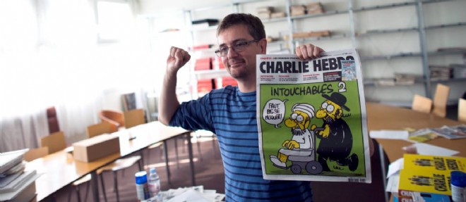 Charb pose en 2012 avec une une de Charlie, "Les Intouchables", qui lui avait valu des menaces de mort.