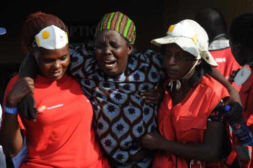 Une femme éplorée est aidée par deux membres de la Croix rouge kenyane dans la salle mortuaire à Nairobi où reposent les cadavres de ceux tués lors du massacre de l'université de Garissa © SIMON MAINA AFP