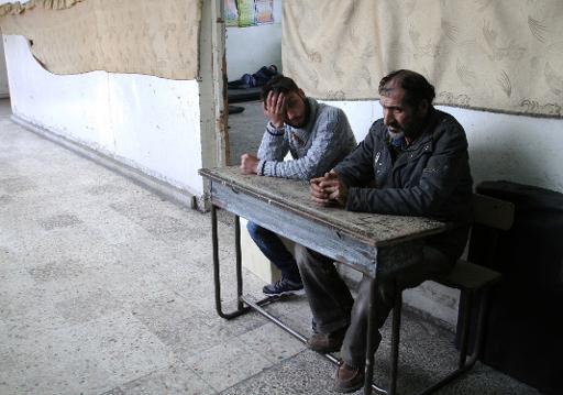 Des Palestiniens qui se sont enfuis du camp de Yarmuk sont assis sur un banc, à l'intérieur d'une école à Damas, le 6 avril 2015 © YOUSSEF KARWASHAN AFP