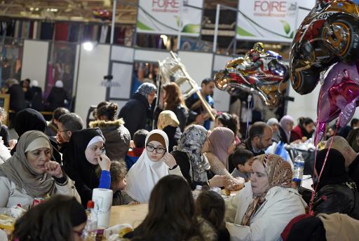 Des visiteurs et visiteuses se retrouvent autour d'un repas, dans les allées du congrès annuel des musulmans au Bourget, le 6 avril 2015 © LOIC VENANCE AFP