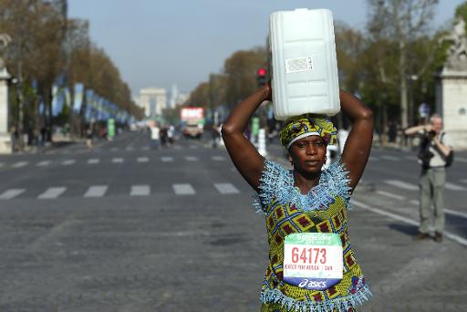 Lors du marathon de Paris, le 12 avril 2015, une Gambienne, Siabatou Sanneh, porte un bidon sur la tête pour sensibiliser l'opinion aux kilomètres parcourus en Afrique pour chercher de l'eau © THOMAS SAMSON AFP