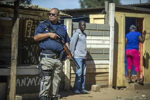 Un policier sud-africain monte la garde devant un magasin tenu par un étranger, dans le village de Primrose près de Johannesburg, le 16 avril 2015 © Mujahid Safodien AFP
