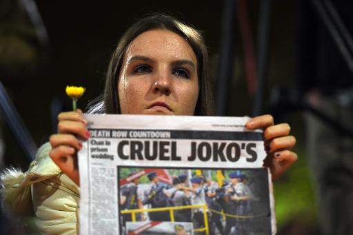 Une femme participant à une veillée le 28 avril 2015 pour les Australiens condamnés mort en Indonésie tient un journal dénonçant la "crauté" du président indonésien Joko Widodo © SAEED KHAN AFP/Archives