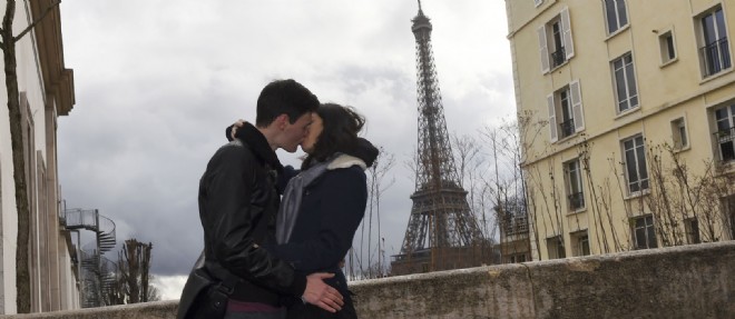 Un couple s'embrasse devant la tour Eiffel a Paris. Photo d'illustration.