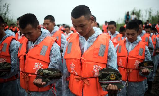 Des secouristes lors de la ceremonie de deuil le 7 juin 2015 sur la berge du Yangtse, devant l'epave du bateau