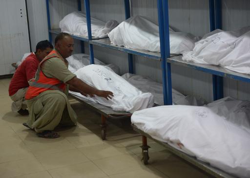 Des volontaires pakistanais placent les corps de victimes d'un attentat contre un bus transportant des membres d'une minorite chiite dans la morgue de Karachi le 13 mai 2015