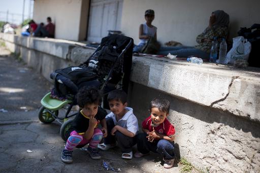 Trois enfants jouent pendant que leurs parents se reposent dans la gare de Demir Kapija, le 15 juin 2015, en Macédoine, en route vers la frontière de la Serbie © ROBERT ATANASOVSKI AFP