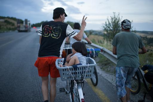 Un groupe de migrants pousse leurs vélos sur une route, le 15 juin 2015, près de la ville de Veles en Macédoine, en route vers la Serbie © ROBERT ATANASOVSKI AFP