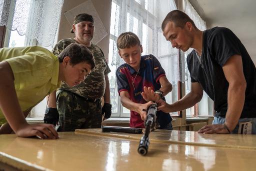 Un jeune garcon apprend a utiliser une kalachnikov sous le regard d'un instructeur, le 17 juin 2015 dans la ville separatiste pro-russe de Khartsyzk, dans l'est de l'Ukraine