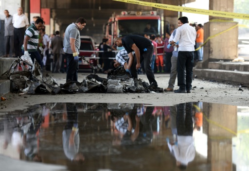 Des experts autour de la voiture piegee utilisee dans un attentat contre le consulat italien le 11 juillet 2015 au Caire