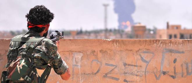 Un combattant kurde du YPG observe la fumee qui s'echappe de la ville syrienne de Hasakeh, le 28 juin.
