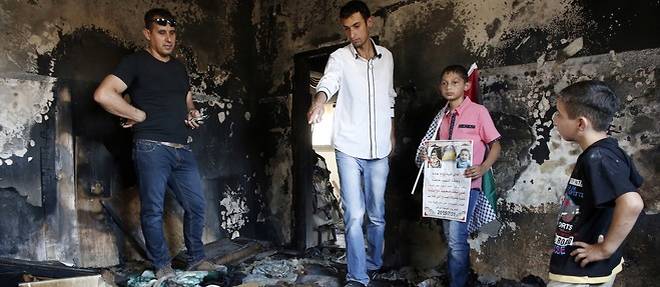 Des Palestiniens sur les ruines de la maison incendiee par des colons ou un bebe de 18 mois est mort.
