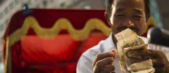 Un homme et des billets de yuans chinois a Pekin, le 28 juillet 2015.