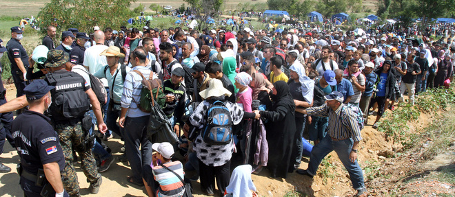 Des migrants syriens attendent devant la frontiere entre Serbie et Macedoine, le 23 aout 2015.