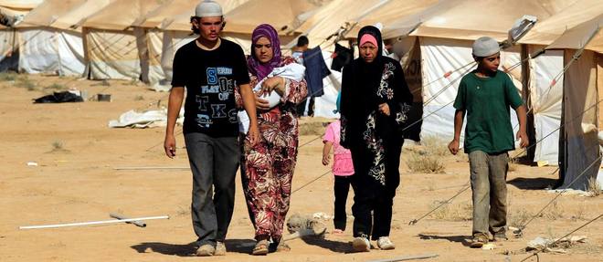 Une famille syrienne marche a proximite de tentes dans le camp de refugies de Zaatari, dans le nord de la Jordanie, en aout 2012.
