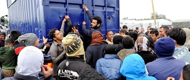 Dans le camp de refugies de Calais. Des migrants s'agrippent a un camion. Monter sur les camions est devenu un jeu. Calais. 5 aout 2015.