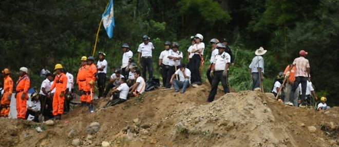 Des secouristes, pompiers et habitants sur les lieux d'un glissement de terrain a Santa Catarina Pinula, a 15 km a l'est de Guatemala, le 2 octobre 2015