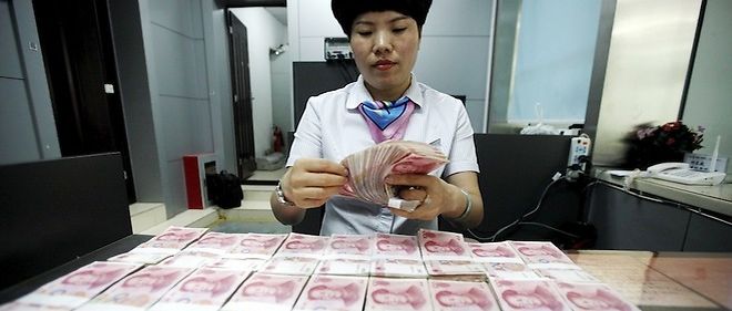 Un employe chinois et des billets de banque a Huaibei, a l'est de la Chine, en 2015.