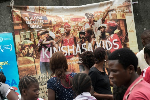 Des passants devant l'affiche du film "Kinshasa Kids" au Lycée Molende à Matete à Kinshasa le 24 septembre 2015 © Junior Kannah AFP/Archives