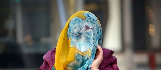 Une femme se protege le visage avec un foulard, a Pekin le 7 decembre 2015