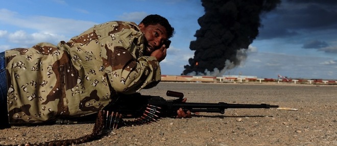 La situation qui prevaut aujourd'hui en Libye rappelle celle qui sert de decor a cette photo avec un rebelle pres de Ras Lanouf et, au fond, la fumee d'un puits de petrole. 