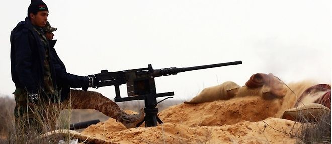 Un soldat de l'armee libyenne observe la fumee noire qui se degage d'un terminal petrolier a Benghazi apres que des hommes de l'Etat islamique y ont mis le feu en mars 2015. 