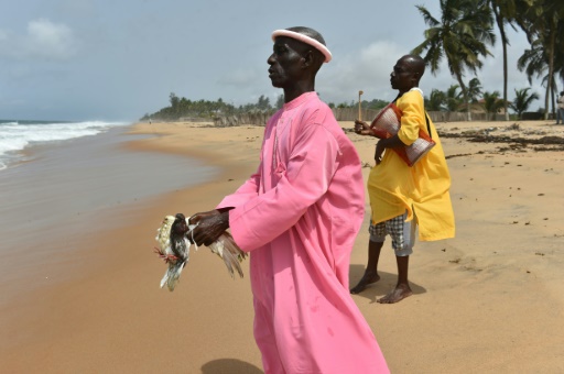 Un croyant tient deux pigeons et avance en direction de la mer, lors d'une prière sur la plage de Grand-Bassam en Côte d'Ivoire, le 1er avril 2016 © ISSOUF SANOGO AFP