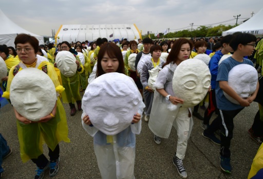 Des proches portent des têtes en papier mâché représentant les 304 victimes du naufrage du ferry Sewol à Ansan (Corée du Sud), le 16 avril 2016 © JUNG YEON-JE AFP