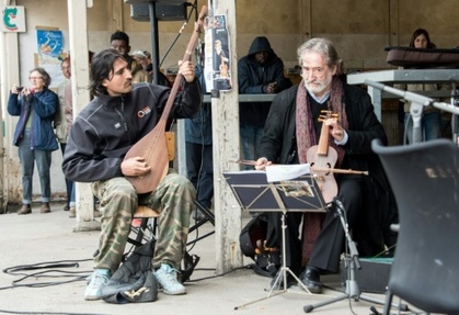 Le chef d'orchestre espagnol Jordi Savall (D) donne un concert pour les migrants de Calais, dans la cour du centre d'hebergement Jules-Ferry, le 16 avril 2016