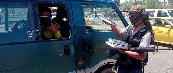 A Mossoul, en 2014. Dans le fief de Daech en Irak, un combattant distribue le Coran. Desormais, mal repondre a des questions sur le livre saint est puni d'amendes.