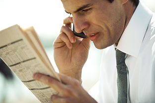 Businessman using cell phone and looking at newspaper, close-up, side view ©Eric Audras / AltoPress / PhotoAlto